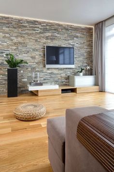 a living room with wood flooring and stone wall