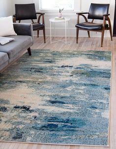 a living room filled with furniture and a rug on top of a hard wood floor