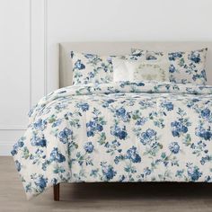 a blue and white floral comforter set on a bed