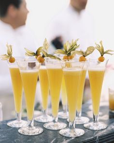 four glasses filled with orange juice and garnished with berries on the rims