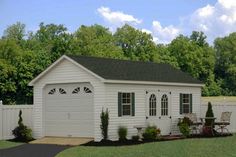 a small white shed sitting in the middle of a yard