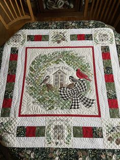 a quilted table topper with a red bird on it and a house in the background