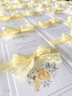 wedding stationery with yellow ribbon and flowers on it, laid out in rows for guests to see