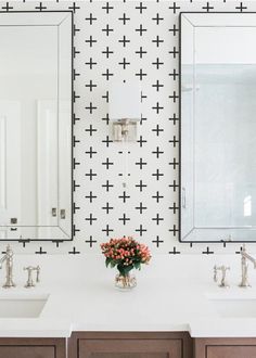 two sinks and mirrors in a bathroom with cross wallpaper on the walls behind them