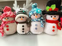 knitted snowmen with hats and scarves are lined up in a row on a table