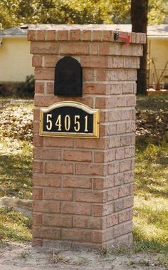 a brick mailbox with a black hat on it's head and address plaque