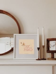 a white mantle topped with a framed photograph and two candles next to a mirror on top of it