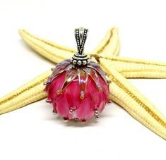 a pink glass beaded pendant sitting on top of a starfish