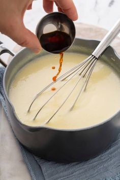 a person is pouring sauce into a pan with whisks on it and an egg beater in the middle