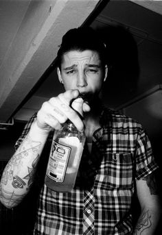 a man with tattoos drinking from a bottle