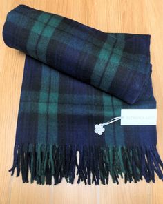 a blue and green plaid blanket with a tag on it sitting on a wooden floor