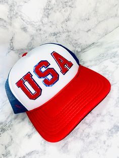 This USA Chenille Trucker Hat is the perfect way to show your patriotic spirit in style! Featuring chenille and a casual good looking trucker hat, it's perfect for sunny days spent outdoors so that you can stay cool and comfortable all summer long. Show your USA pride and look cute every day with this patriotic hat. Fourth Of July Trucker Hats, Summer Trucker Snapback Hat, Summer Patriotic Trucker Hat With Curved Brim, Summer Trucker Baseball Cap With Visor, Patriotic Adjustable Hat For Independence Day, Patriotic White Hat For Summer, Trendy Cap For 4th Of July, White Baseball Cap Trucker Hat For 4th Of July, Patriotic Summer Snapback Trucker Hat