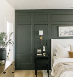 a bedroom with dark green walls and white bedding