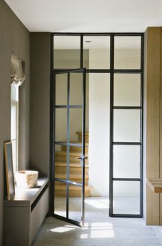 an empty hallway leading to a staircase with glass doors on both sides and a mirror in the middle