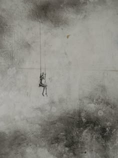 a black and white photo of a person hanging on to a rope in the air