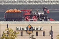 an old fashioned train with oranges on it is parked in front of the minute maid