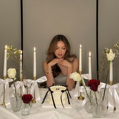 a woman sitting in front of a table with flowers and candles