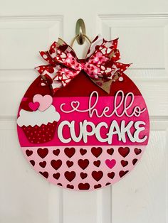 a hello cupcake door hanger hanging on a white door with red and pink hearts