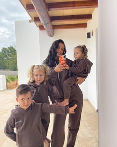 a woman taking a selfie with her three children in matching brown tracksuits