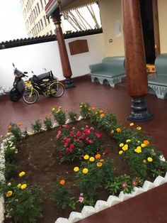 a bike is parked in the middle of a flower garden on a patio with benches