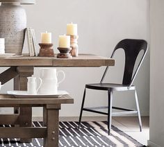 a dining room table with candles on it and two chairs next to it in front of the table