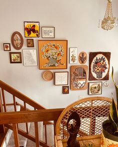 there are many framed pictures on the wall above the chair and stair case in this room