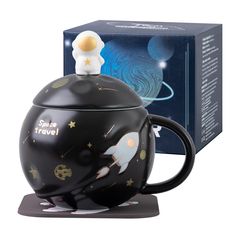 a black teapot with an astronaut design on it and a space travel mug next to it