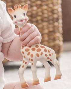 a small giraffe toy being held by a baby