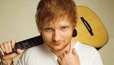 a young man holding an acoustic guitar over his shoulder