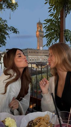 two beautiful women sitting at a table eating food