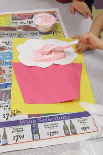 two people are making cupcakes out of paper on a table with coupons