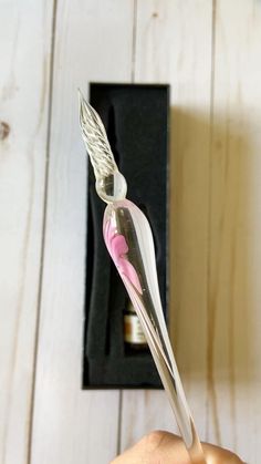 a toothbrush with pink and white bristles is being held by someone's hand