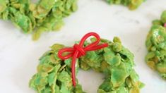 christmas wreath shaped cookies with red ribbon tied around them on a white counter top, ready to be eaten