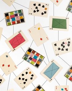 playing cards are hanging from strings on a white wall with squares and shapes painted on them