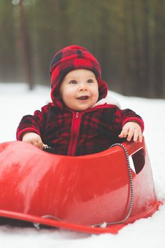 a baby sitting in a sled on the snow