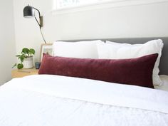 a bed with white sheets and red pillows