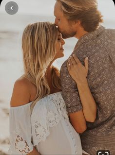 a man and woman are kissing on the beach while holding each other's hands