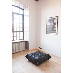 a black ottoman sitting on top of a hard wood floor in front of a window