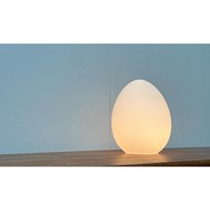 an egg shaped light sitting on top of a wooden table