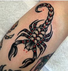 a scorpion tattoo with red beads on it