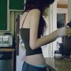 a woman standing in a kitchen next to a refrigerator