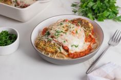 a white bowl filled with pasta covered in sauce and parmesan cheese on top