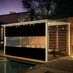 an outdoor living area with patio furniture and lights on the side of it at night