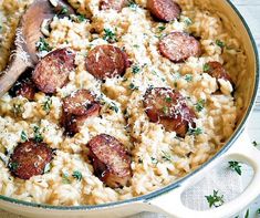 a skillet filled with pasta and sausage covered in parmesan cheese, garnished with parsley