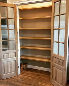 an empty walk in closet with wooden shelves and glass doors on both sides, open to reveal another room