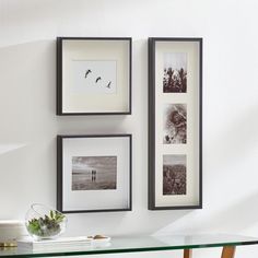 three framed pictures hang on the wall above a glass table