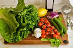 lettuce, tomatoes, cucumbers and other vegetables on a cutting board