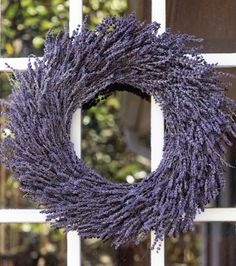 a lavender wreath hanging on the side of a window