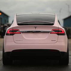 the back end of a pink car parked in a parking lot