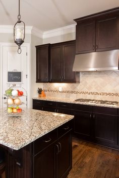 a kitchen with granite counter tops and dark wood cabinets, along with an island in the middle